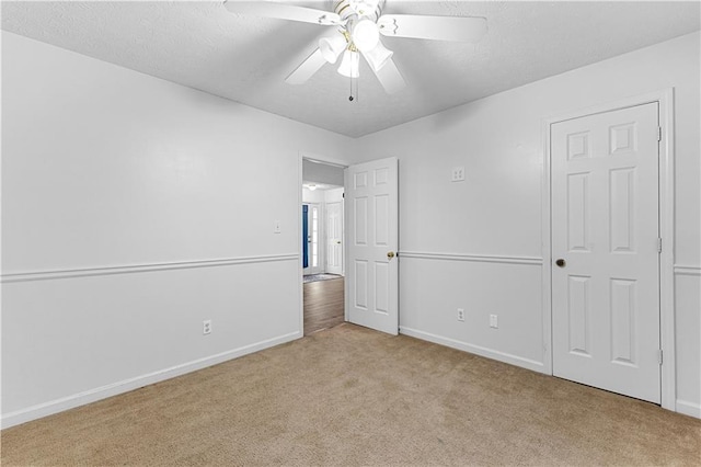 unfurnished bedroom with a textured ceiling, carpet flooring, baseboards, and ceiling fan