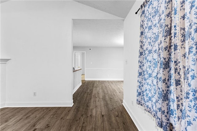 hall with vaulted ceiling, baseboards, and dark wood-style flooring
