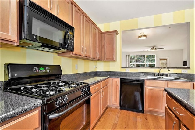 kitchen with ceiling fan, sink, black appliances, dark stone countertops, and light wood-type flooring