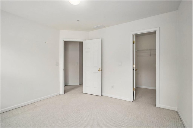 unfurnished bedroom featuring light carpet, a closet, and a walk in closet