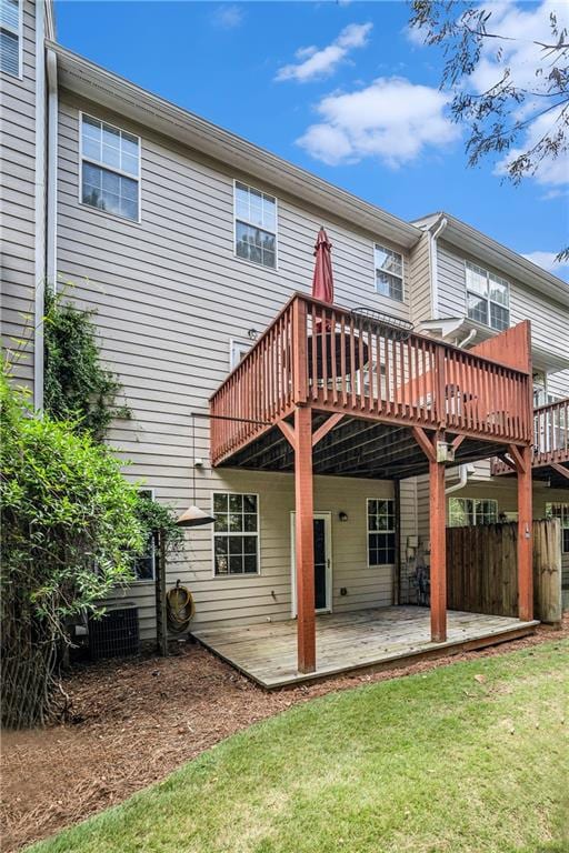 rear view of property featuring a yard, a wooden deck, and a patio area