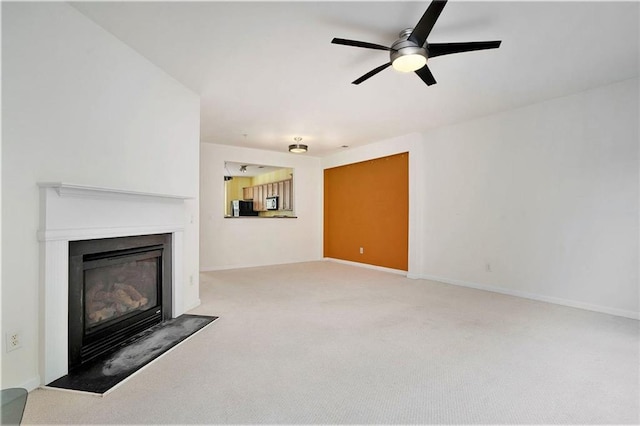 unfurnished living room featuring ceiling fan and light colored carpet