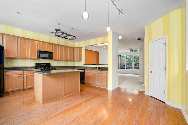 kitchen featuring black appliances, a center island, light hardwood / wood-style flooring, ceiling fan, and sink