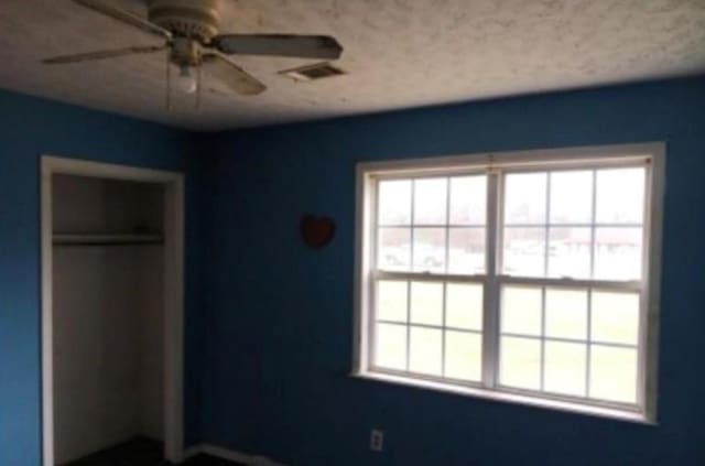unfurnished bedroom with multiple windows, a ceiling fan, a closet, and visible vents