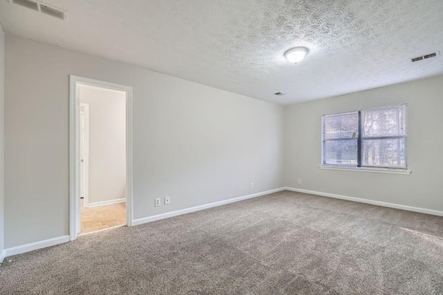 spare room featuring carpet floors and a textured ceiling