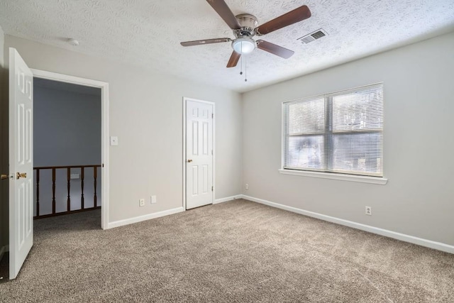 carpeted spare room with a textured ceiling and ceiling fan