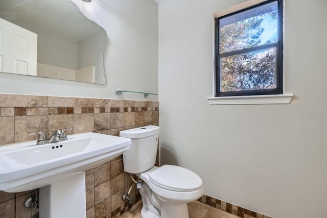 bathroom with sink, tile patterned flooring, tile walls, and toilet