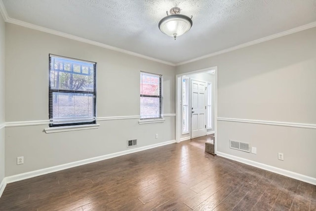 empty room featuring dark wood-type flooring, a textured ceiling, and ornamental molding