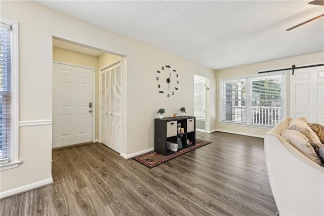 unfurnished living room featuring dark wood-type flooring, a barn door, and ceiling fan