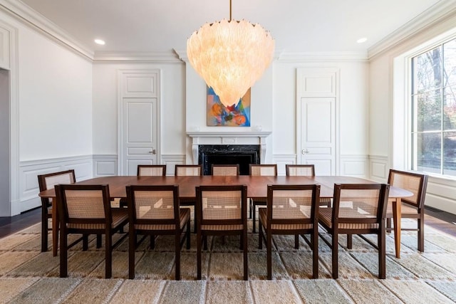 dining space with a premium fireplace, plenty of natural light, a notable chandelier, and ornamental molding