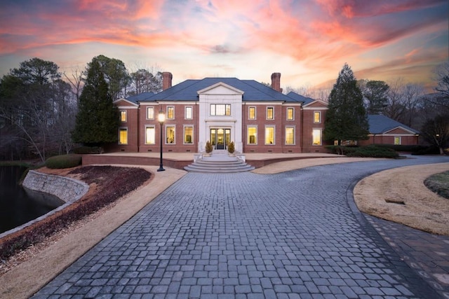 greek revival house featuring curved driveway, french doors, and a chimney