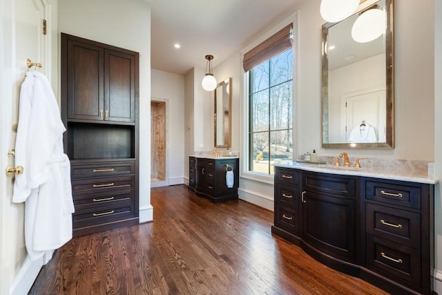 full bathroom with a sink, baseboards, two vanities, and wood finished floors