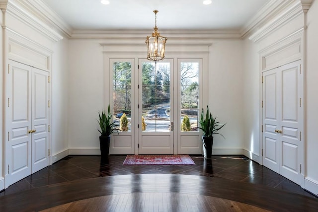 entrance foyer with baseboards, dark wood-type flooring, an inviting chandelier, and crown molding