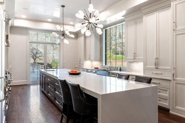 kitchen with backsplash, a center island, dark wood-type flooring, a raised ceiling, and a sink