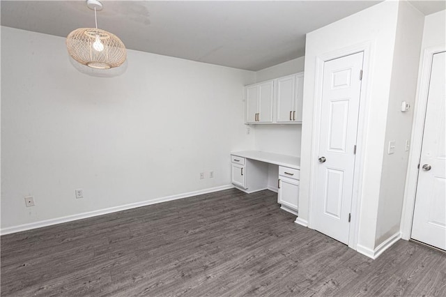 unfurnished office featuring built in desk and dark hardwood / wood-style floors