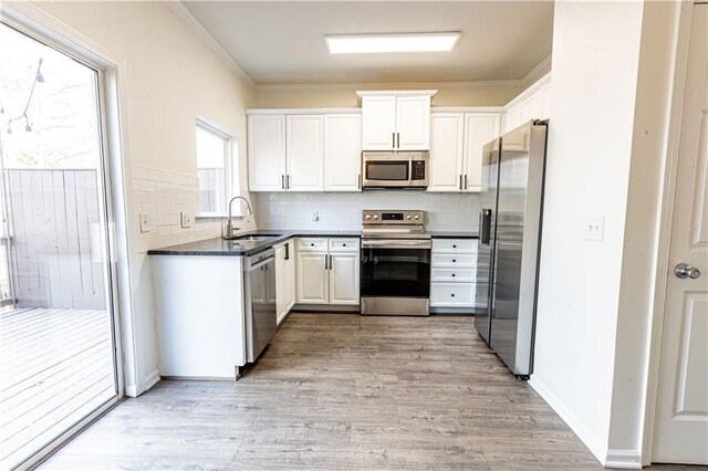 kitchen with sink, crown molding, light hardwood / wood-style flooring, appliances with stainless steel finishes, and white cabinetry