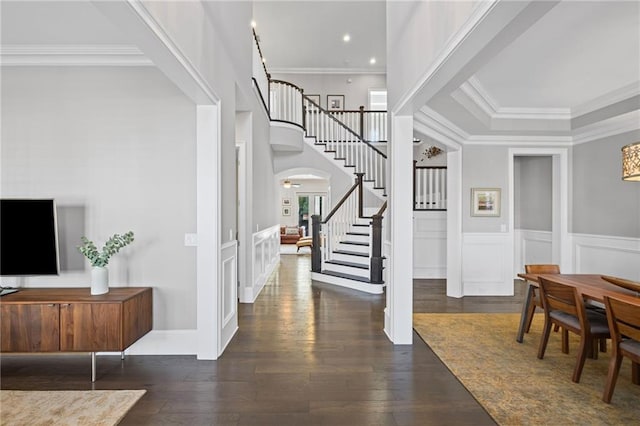 foyer entrance with hardwood / wood-style flooring, stairway, a decorative wall, and crown molding