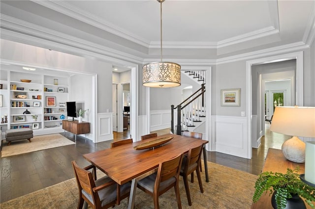 dining space with hardwood / wood-style floors, stairs, wainscoting, crown molding, and a decorative wall