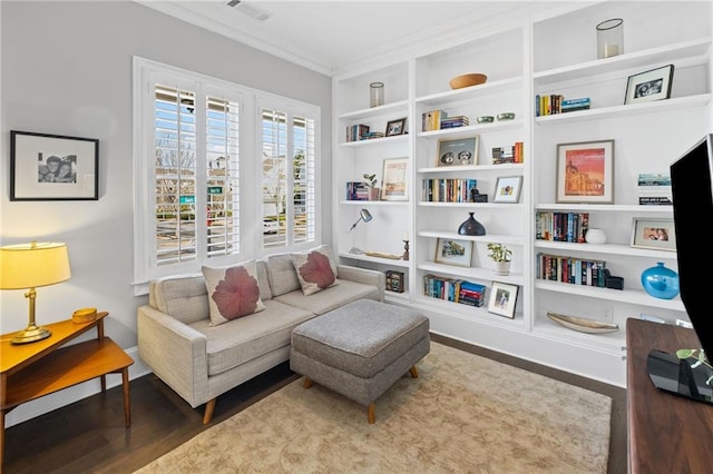 living area featuring visible vents, built in shelves, wood finished floors, and ornamental molding