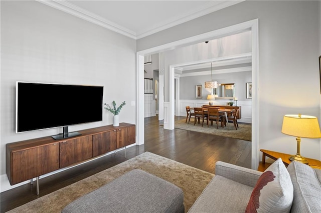 living area with a decorative wall, wainscoting, crown molding, and wood finished floors