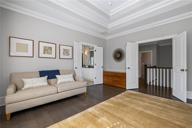 living room with crown molding, wood finished floors, visible vents, and a raised ceiling