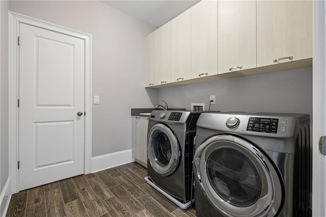 clothes washing area with baseboards, wood finish floors, separate washer and dryer, cabinet space, and a sink