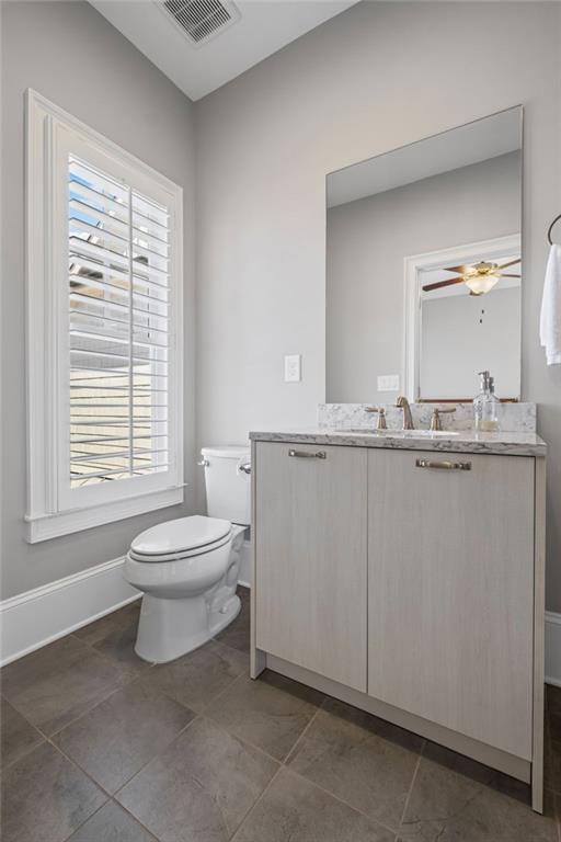 bathroom with vanity, a ceiling fan, baseboards, visible vents, and toilet