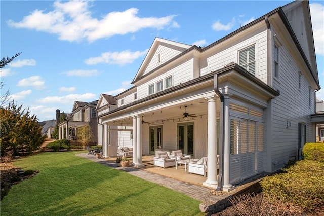 rear view of property featuring an outdoor living space, ceiling fan, french doors, a yard, and a patio area