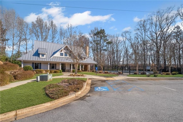 view of front of property featuring a standing seam roof, a front yard, a chimney, and metal roof