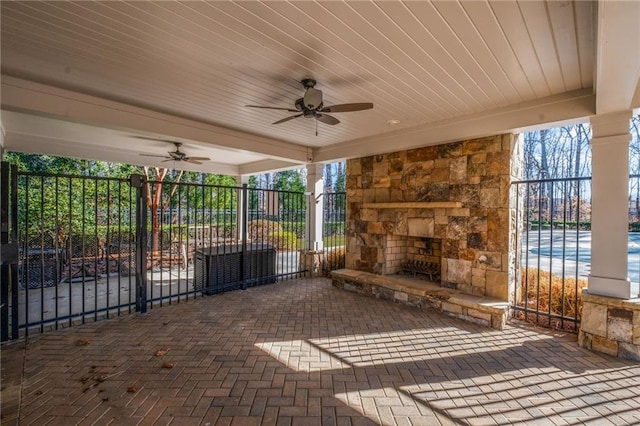 view of patio featuring a ceiling fan, fence, and an outdoor stone fireplace