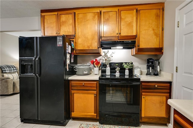 kitchen featuring light tile patterned flooring, a textured ceiling, and black appliances