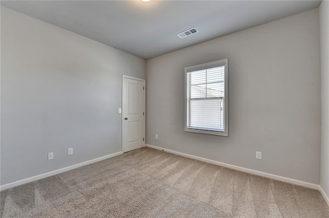 spare room with carpet, visible vents, and baseboards