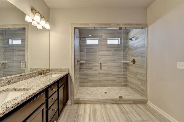 full bathroom with a sink, a shower stall, and double vanity