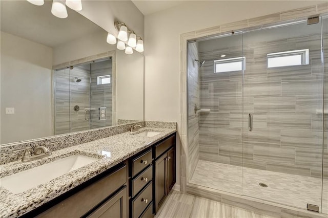 full bath featuring double vanity, a stall shower, and a sink