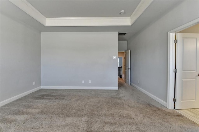 empty room with carpet floors, visible vents, baseboards, ornamental molding, and a raised ceiling