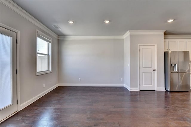 empty room featuring ornamental molding, dark wood-style flooring, visible vents, and baseboards