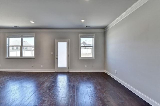 spare room with ornamental molding, dark wood-type flooring, visible vents, and baseboards