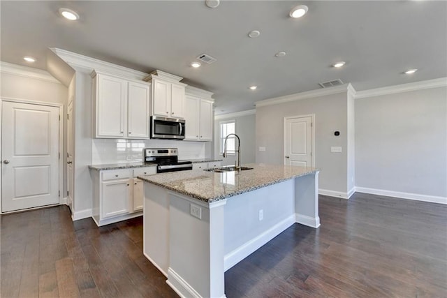 kitchen with appliances with stainless steel finishes, visible vents, a sink, and an island with sink