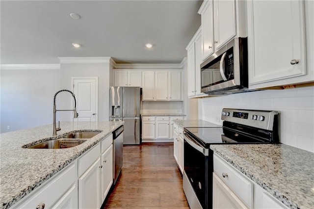 kitchen featuring stainless steel appliances, a sink, white cabinetry, ornamental molding, and dark wood finished floors