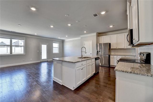 kitchen featuring visible vents, appliances with stainless steel finishes, ornamental molding, open floor plan, and a sink