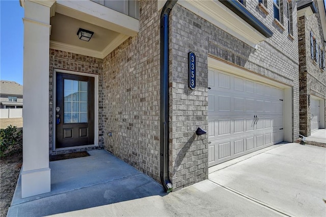 property entrance featuring concrete driveway, brick siding, and an attached garage