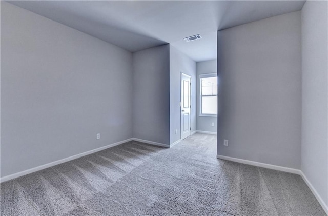 carpeted empty room featuring baseboards and visible vents