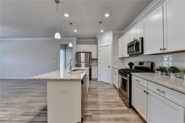 kitchen featuring light stone countertops, white cabinetry, hanging light fixtures, an island with sink, and appliances with stainless steel finishes