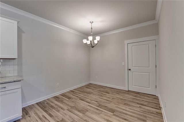 unfurnished dining area with crown molding, light hardwood / wood-style floors, and a notable chandelier