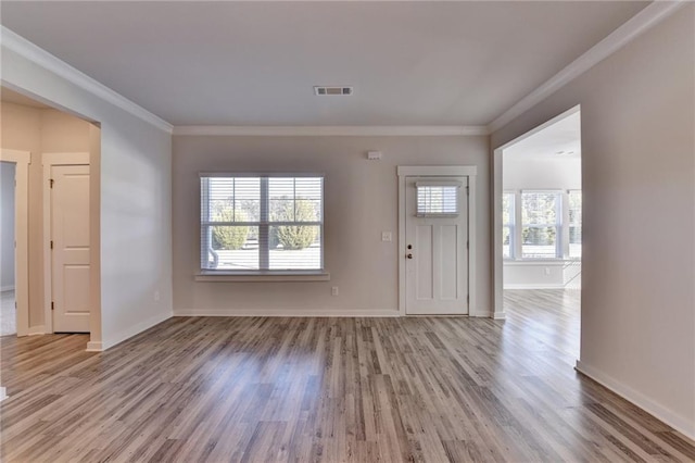 foyer entrance featuring a healthy amount of sunlight, crown molding, and light hardwood / wood-style flooring