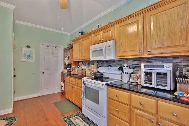 kitchen featuring white appliances, dark stone counters, crown molding, light hardwood / wood-style floors, and tasteful backsplash