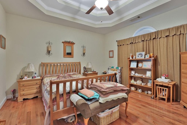 bedroom with crown molding, ceiling fan, hardwood / wood-style flooring, and a raised ceiling