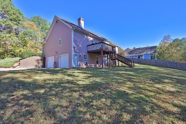 rear view of property with a wooden deck, a garage, and a lawn