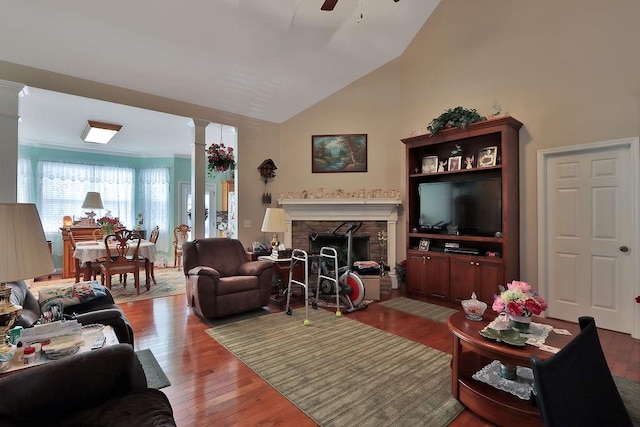 living room with ornate columns, hardwood / wood-style flooring, a fireplace, high vaulted ceiling, and ceiling fan