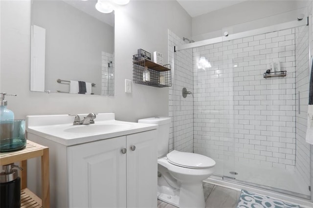 full bath featuring a stall shower, vanity, and toilet